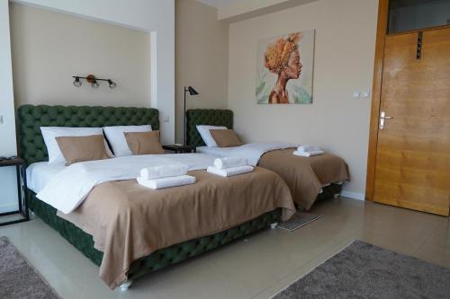 two beds in a bedroom with a green headboard at Sweet69apartments JP in Niš