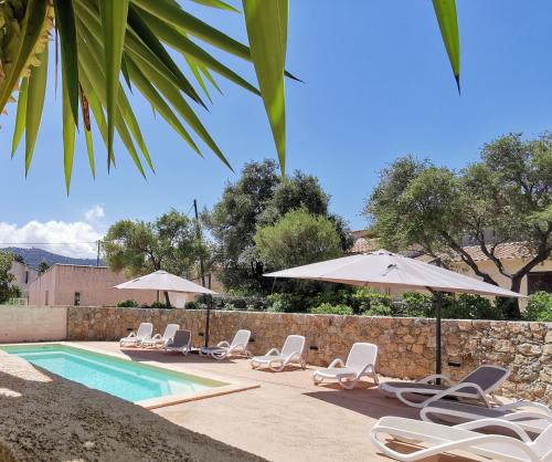 a group of chairs and umbrellas next to a swimming pool at Résidence Saint Michel in LʼÎle-Rousse