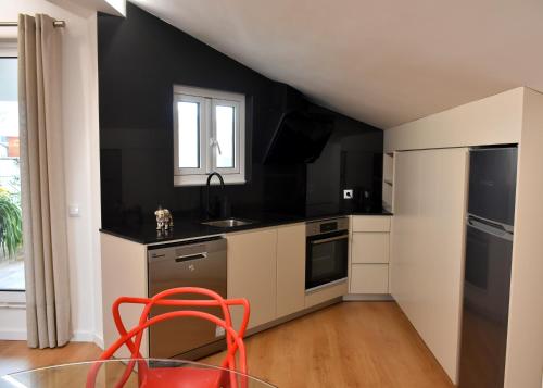 a kitchen with a red chair and a black wall at Orchid House - T1 Apartment in Braga
