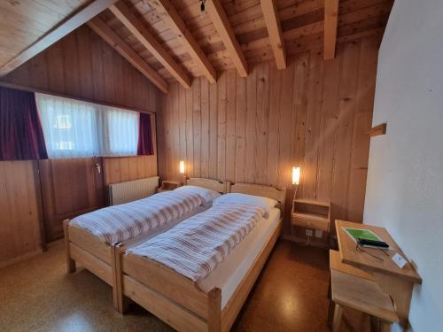 a bedroom with two beds in a wooden room at Hotel Astoria in Ulrichen