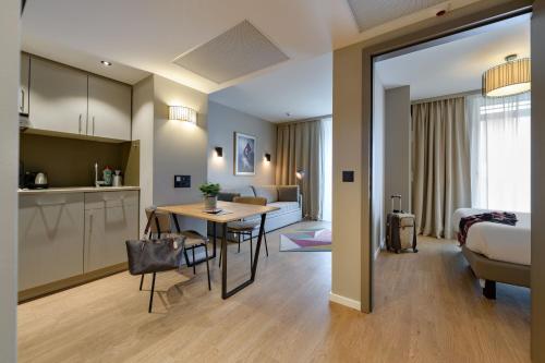 a kitchen and a living room with a table in a room at Aparthotel Adagio Zurich City Center in Zurich