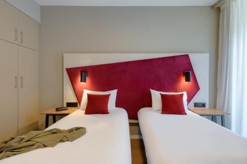 two beds in a room with a red headboard at Aparthotel Adagio Zurich City Center in Zurich