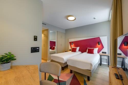 a hotel room with two beds and a red headboard at Aparthotel Adagio Zurich City Center in Zurich