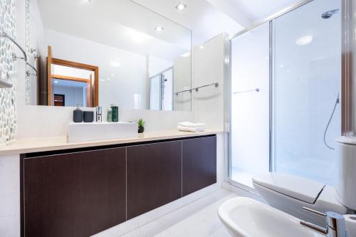 a bathroom with a sink and a toilet and a mirror at Baía da Luz - Sea View Luxury Apartment in Luz
