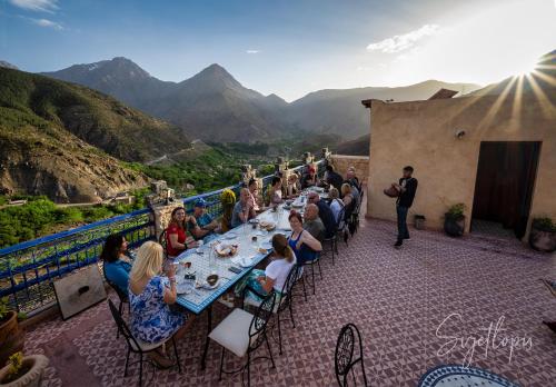 a group of people sitting at a table on a balcony at Toubkal Ecolodge in Imlil