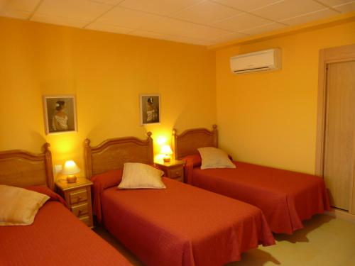 Hostal Mirador de Avila في أفيلا: سريرين في غرفة بجدران صفراء