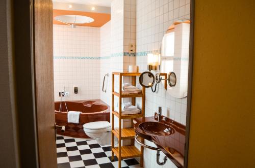 ein Badezimmer mit einer Badewanne, einem WC und einem Waschbecken in der Unterkunft Haus des Volkes - Das Bauhaushotel in Probstzella