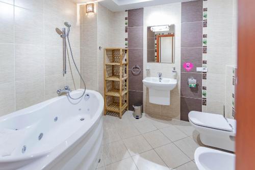 ein Badezimmer mit einer Badewanne, einem Waschbecken und einem WC in der Unterkunft VacationClub - Osiedle Podgórze 1B Apartament 6 in Szklarska Poręba
