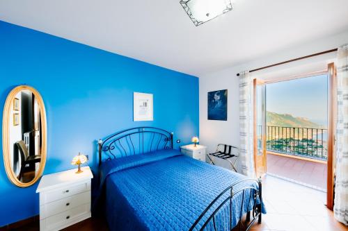 a blue bedroom with a bed and a balcony at Appartamento Elisa in Villa Laura in Scala