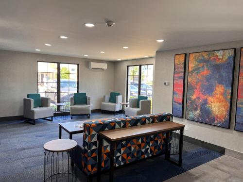 a waiting room with a couch and chairs and paintings at La Quinta Inn Lexington-Horse Park in Lexington