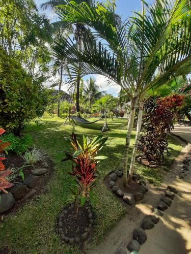 a garden with two palm trees and a hammock at Le Moya Beach in Nosy Be