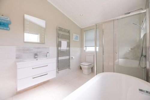 baño blanco con bañera y aseo en Marshwiggle, Aldeburgh, en Aldeburgh