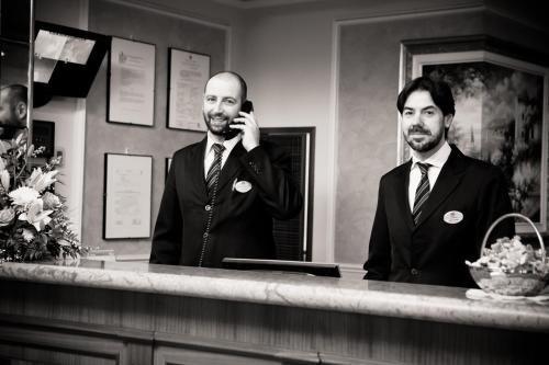 a man talking on a cell phone in front of a mirror at Santa Barbara Hotel in San Donato Milanese