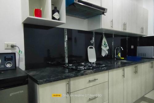 a kitchen with white cabinets and a black counter top at Hermoso Departamento - Zona Miraflores in Tarija