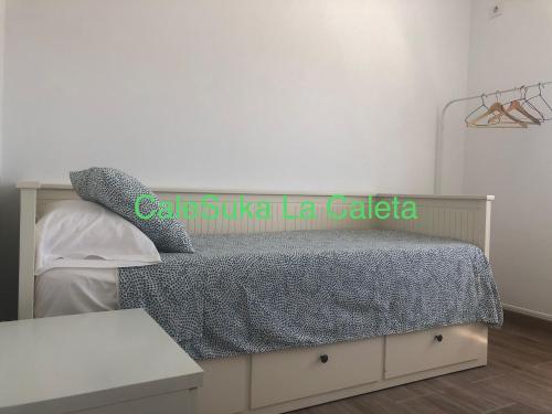 sypialnia z łóżkiem z szarą kołdrą w obiekcie CaleSuka La Caleta w Kadyksie