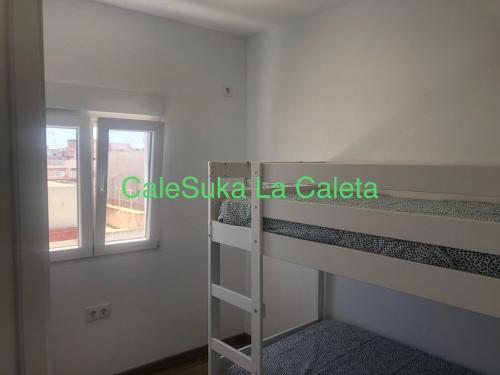 Pokój z łóżkiem piętrowym i oknem w obiekcie CaleSuka La Caleta w Kadyksie