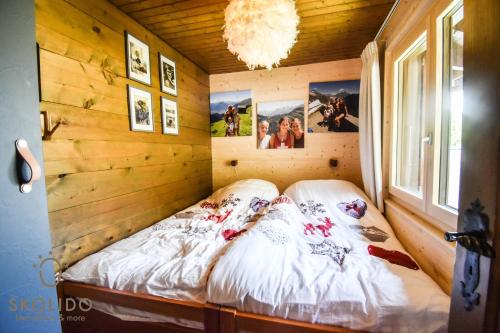 Cama en habitación con pared de madera en Ferienwohnung Chalet Tamalone, Mörel, en Breiten