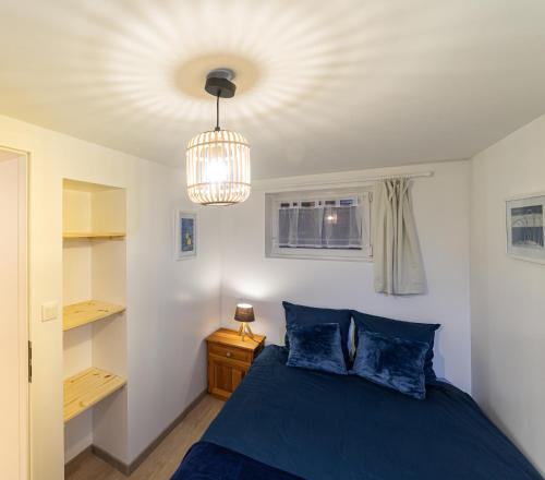 una camera da letto con un letto blu e un lampadario di Les coquelicots, calme, jardin a Colmar