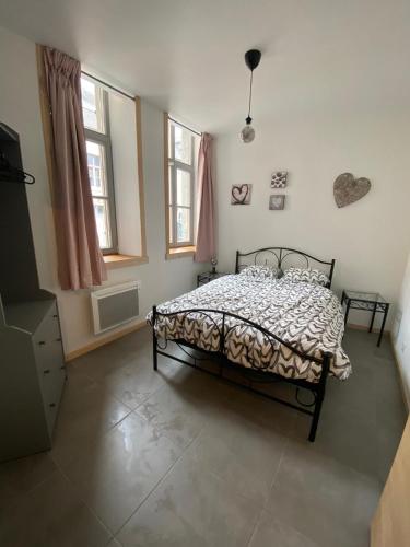 une chambre avec un lit et deux fenêtres dans l'établissement APPARTEMENT neuf au centre ville situé au rdc avec terrasse, à Givet