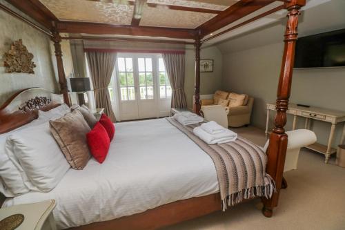 een grote slaapkamer met een groot bed met witte lakens en rode kussens bij Bodmin Country House in Bodmin