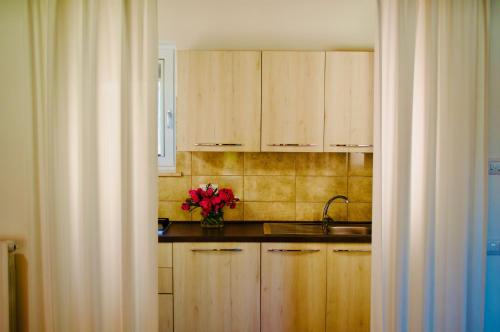 a kitchen with wooden cabinets and a vase of flowers at Villetta Bianca Pisticci-Matera in Pisticci