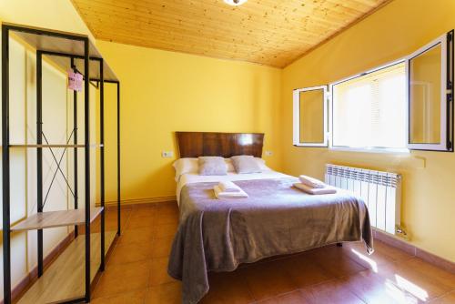 1 dormitorio con 1 cama en una habitación con paredes amarillas en O Cubelo, en Arzúa