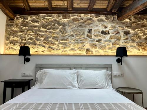 a bedroom with a stone wall behind a bed at A Parada House by Kev in Parada del Sil