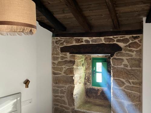 a room with a stone wall with a green window at A Parada House by Kev in Parada del Sil