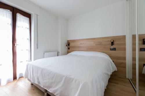 1 dormitorio con cama blanca y cabecero de madera en APARTAMENTOS NIZA, en Santander