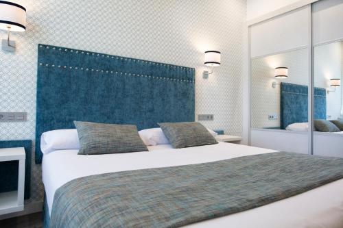 a bedroom with a large bed with a blue headboard at Hotel Santa Cruz in Cangas de Onís