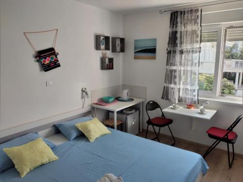 een slaapkamer met een blauw bed en een bureau bij Apartments Cappuccino in Podstrana
