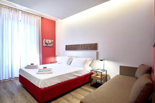 DONATELLO11 Milan apartments في ميلانو: غرفة نوم حمراء وبيضاء بسرير واريكة