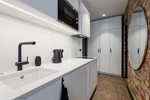 eine weiße Küche mit einem Waschbecken und einem Spiegel in der Unterkunft Old Town Studio Apartment Aia 5a in Tallinn