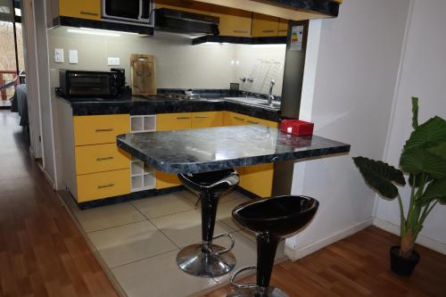 cocina con armarios amarillos y encimera negra en Cabañas Habitainer BordeRio en Concepción