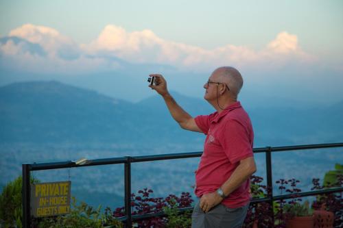 a man taking a picture of the view from a mountain at Raniban Retreat in Pokhara