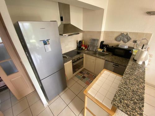 une petite cuisine avec un réfrigérateur et un évier dans l'établissement Chaleureux appartement T4 cosy, Font Romeu Odeillo Via, à Font-Romeu-Odeillo-Via