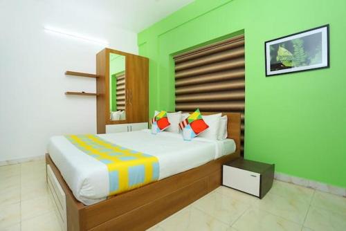 um quarto com uma cama grande e uma parede verde em The Solo Apartments Kadavanthra em Ernakulam