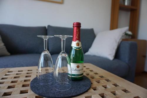 a bottle of wine and two glasses on a table at Ferienwohnung Wiesengrund in Bad Endbach