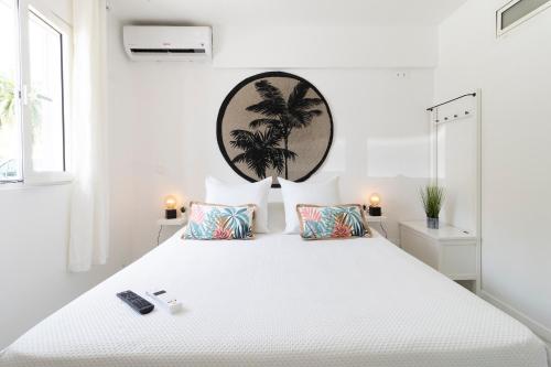 Anse Marcel 的住宿－Kaffa50 - Plage& 3Piscines - Anse Marcel，白色卧室设有一张白色大床,墙上挂着棕榈树