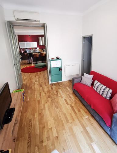 - un salon avec un canapé rouge et du parquet dans l'établissement Our home, Cozy Apartment two minutes from the sea - Clima, à Nice
