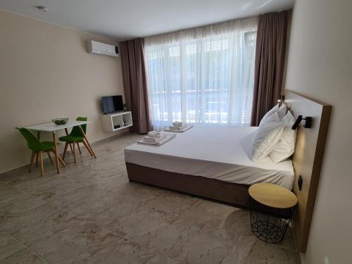 a bedroom with a bed and a table and a window at Aparthotel Happy in Primorsko