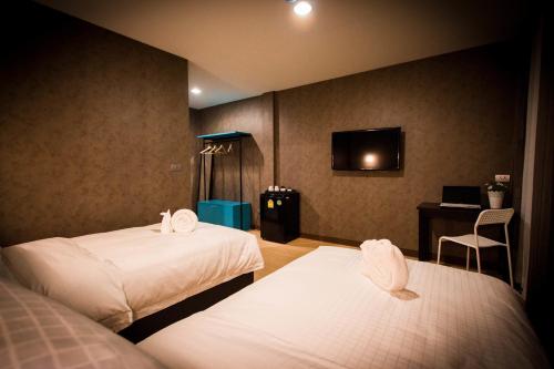 a hotel room with two beds and a television at C U Inn Bangkok - SHA Plus in Bangkok