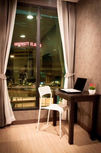 a desk with a laptop and a chair next to a window at C U Inn Bangkok in Bangkok