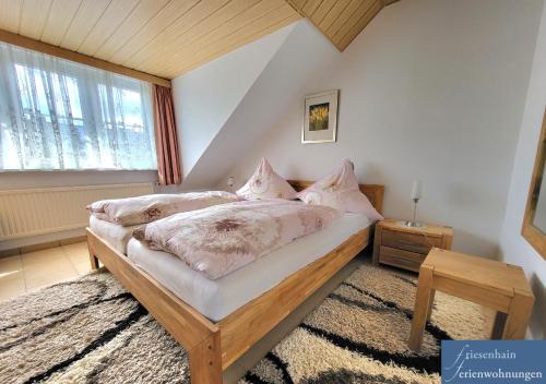 a bedroom with a bed and a window at Friesenhain Ferienwohnungen in Sankt Peter-Ording