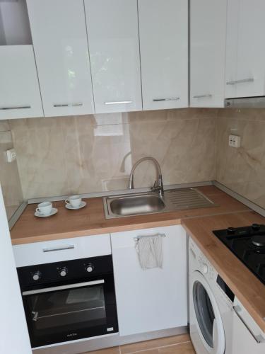 a kitchen with white cabinets and a sink and a dishwasher at Cozy Residence in Bucharest