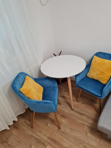 due sedie blu e un tavolo bianco in una stanza di Cozy Garden Residence a Bucarest