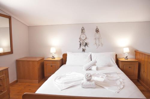 1 dormitorio con 1 cama blanca con sábanas y lámparas blancas en STUDIOS ATHENA en Megalochori