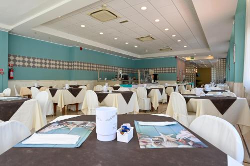 a dining room with tables and white chairs at Amadei Hotel Promenade in Pesaro