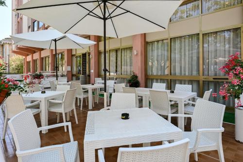 a restaurant with white tables and chairs and umbrellas at Amadei Hotel Promenade in Pesaro