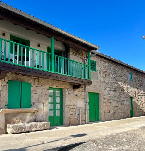 a building with green doors and a balcony at A Parada House by Kev in Parada del Sil